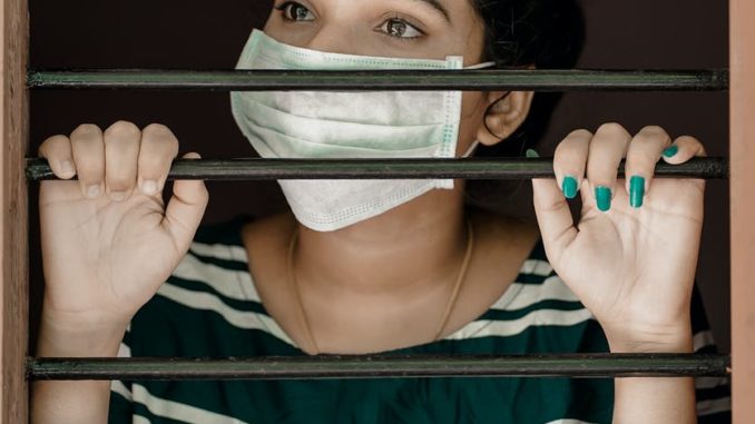 woman in green and white stripe shirt covering her face with white mask